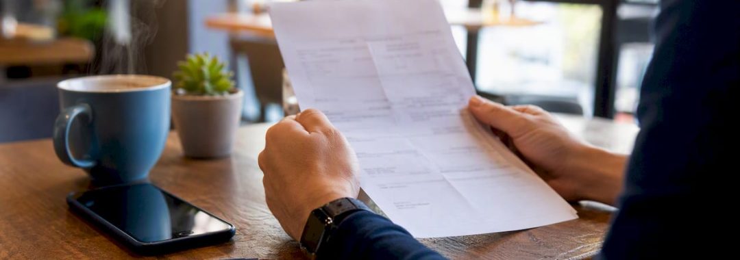 Hands holding Portuguese payslip and smartphone