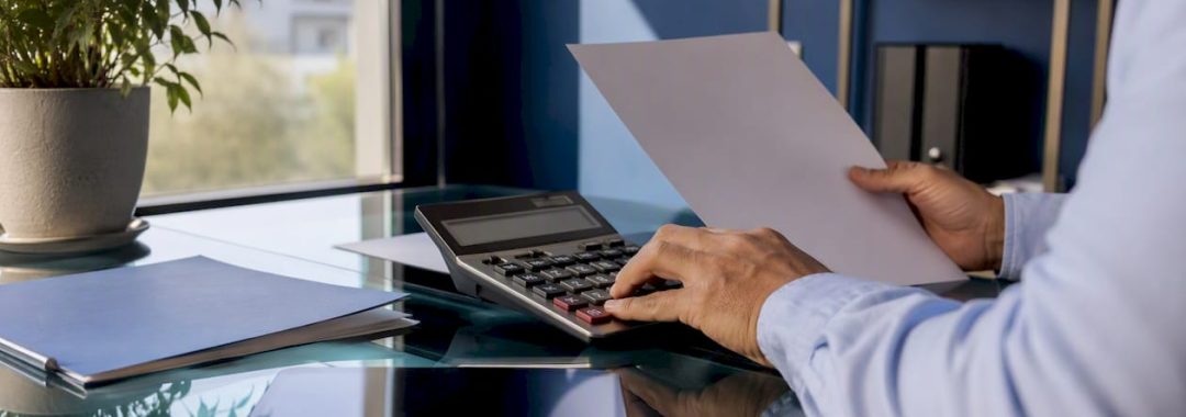 Hands calculating salary with calculator and paycheck