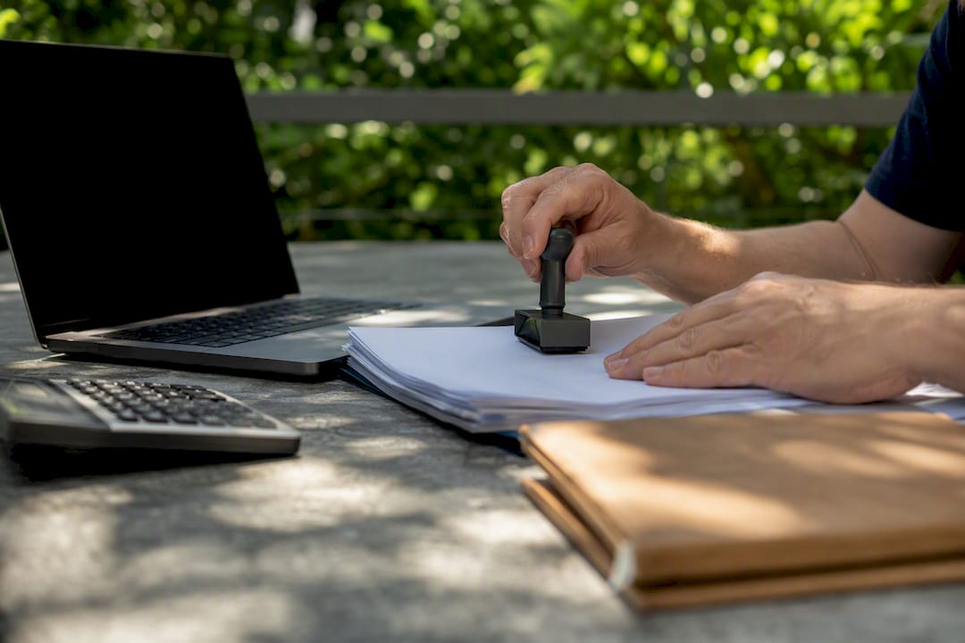 Hands stamping payroll documents on office desk